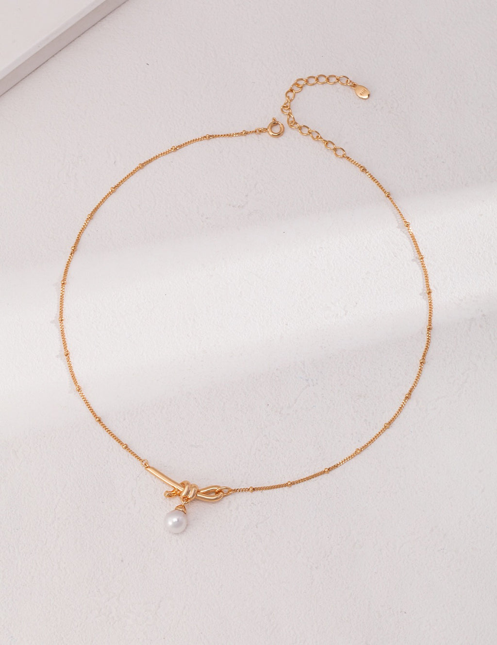 18K gold plated 925 silver knot necklace with natural pearl pendant on white background