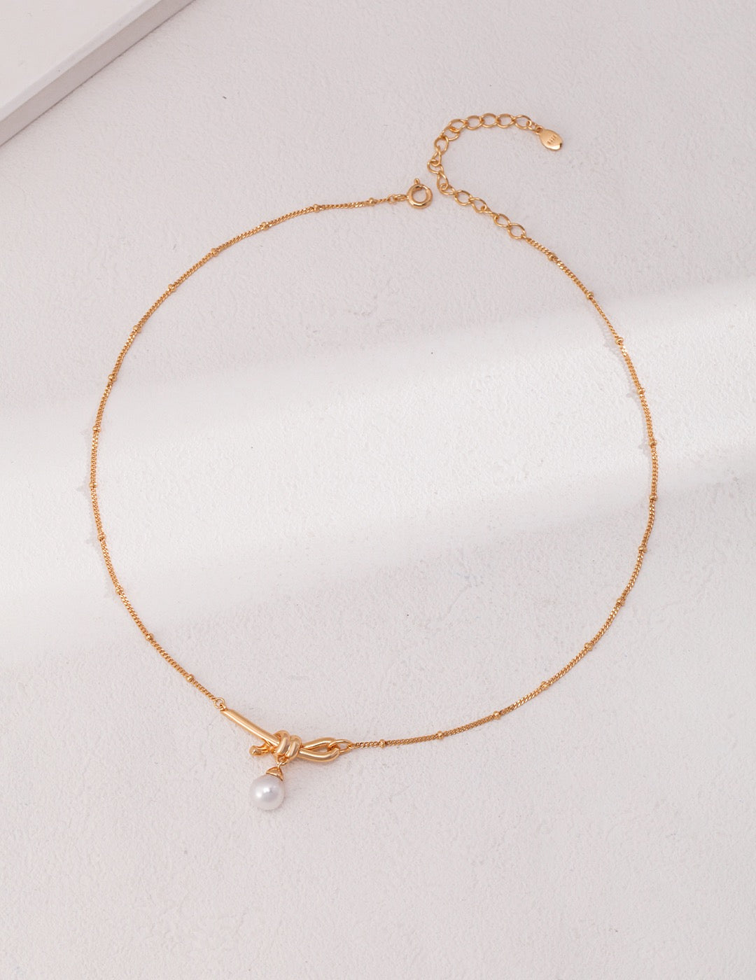 18K gold plated 925 silver knot necklace with natural pearl pendant on white background