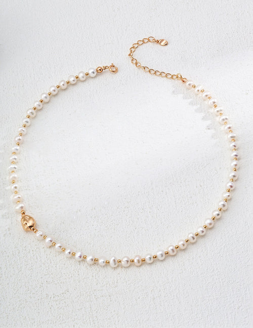 Natural freshwater pearl necklace with 18K gold and white gold plated 925 silver beads on white textured background