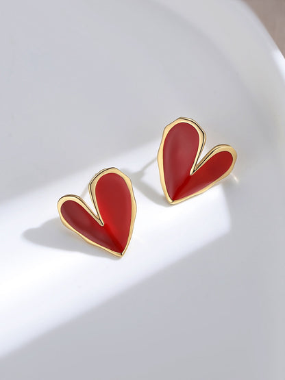 Gold and red enamel glaze heart stud earrings with asymmetrical design on white background