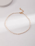 Minimalist freshwater pearl choker with gold accents displayed on soft white background