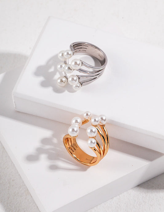 Modern gold and silver pearl rings with shell pearls on white display blocks