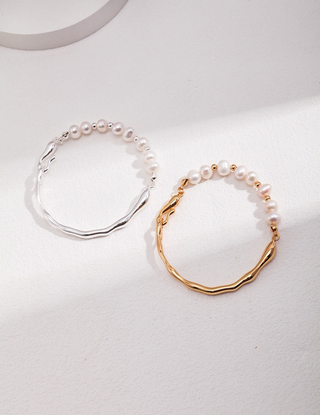 Wavy bracelet in 18K gold and 925 silver with natural freshwater pearls on a white background