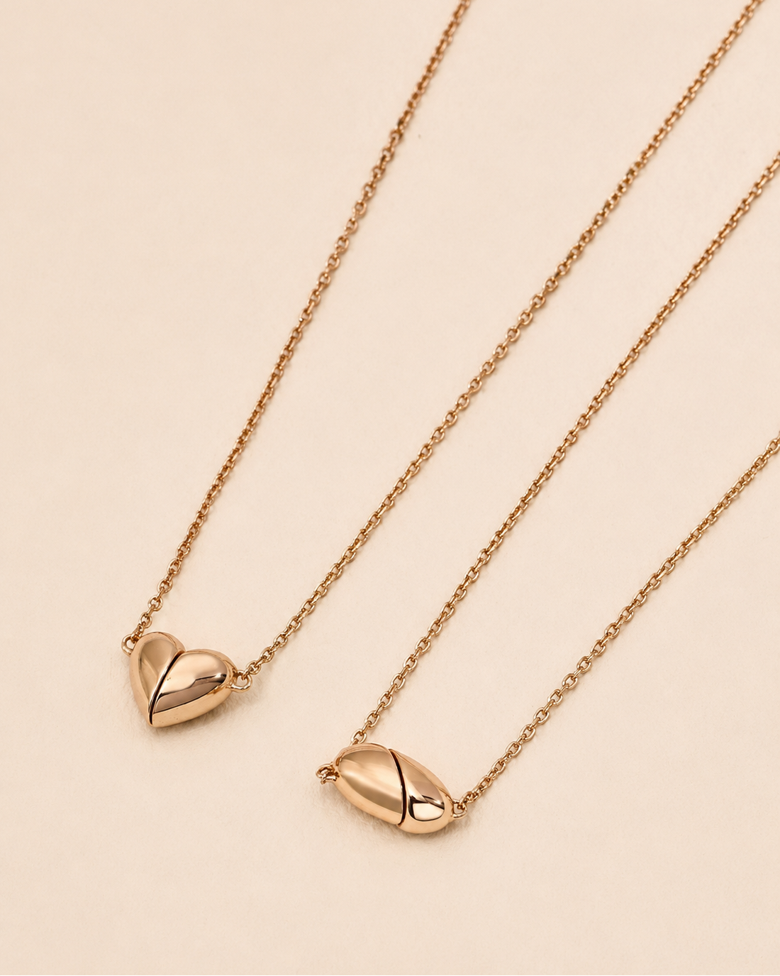 Comparison of heart-shaped and oval magnetic necklaces in 18K gold-plated sterling silver on an ivory background.