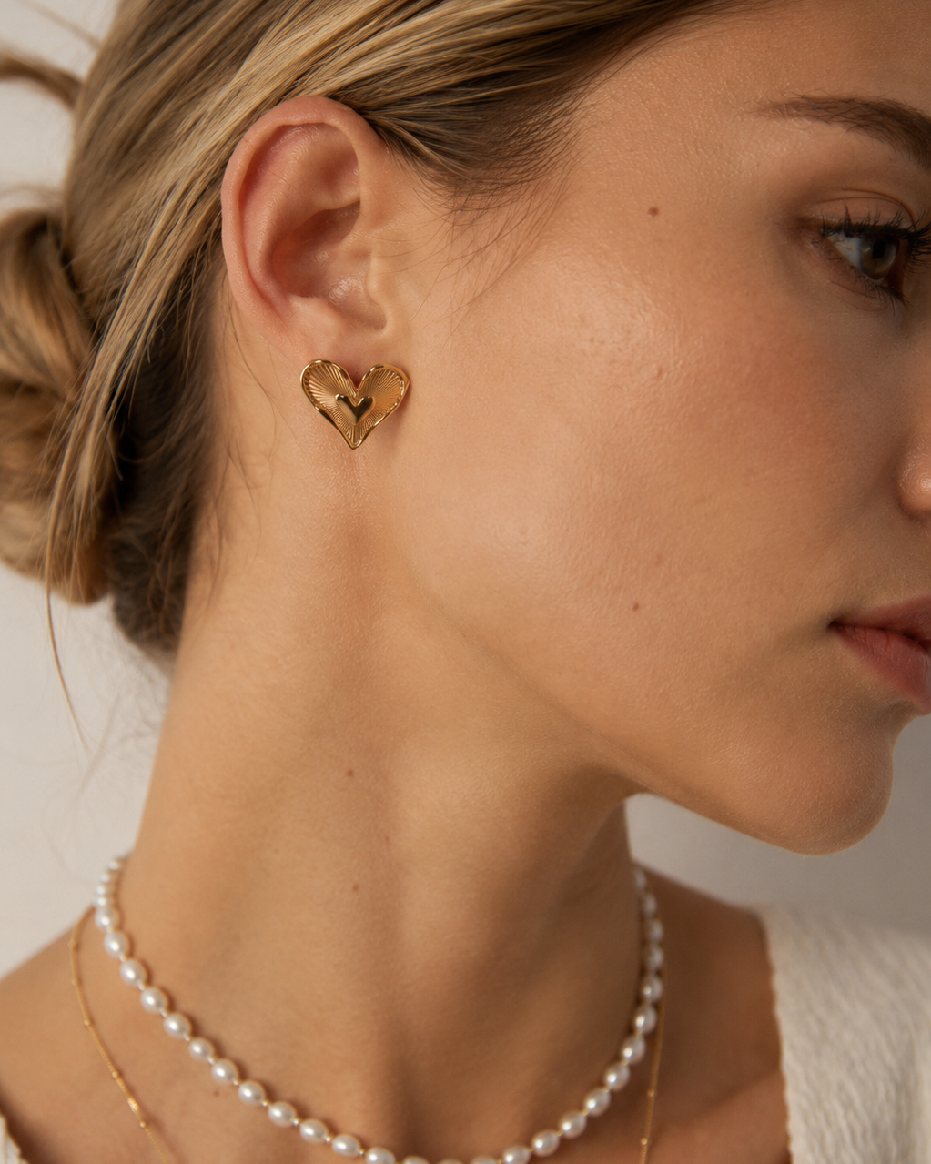 Close-up view of Amour Radiance heart stud earrings featuring a vintage-inspired heart design and radiant texture, worn by a European model.