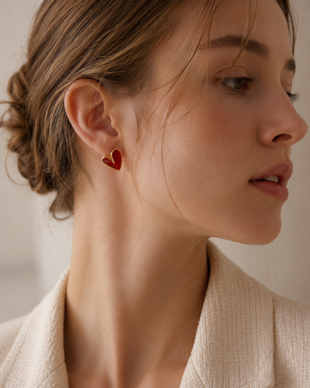 Woman wearing red enamel heart stud earrings in S925 sterling silver with 18K gold plating.