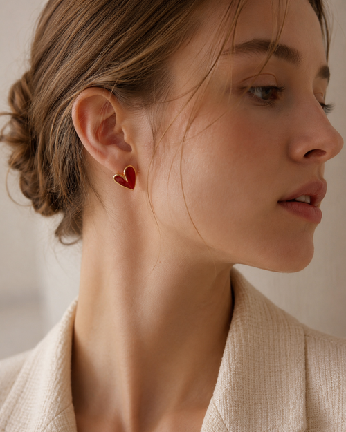 Woman wearing red enamel heart stud earrings in S925 sterling silver with 18K gold plating.