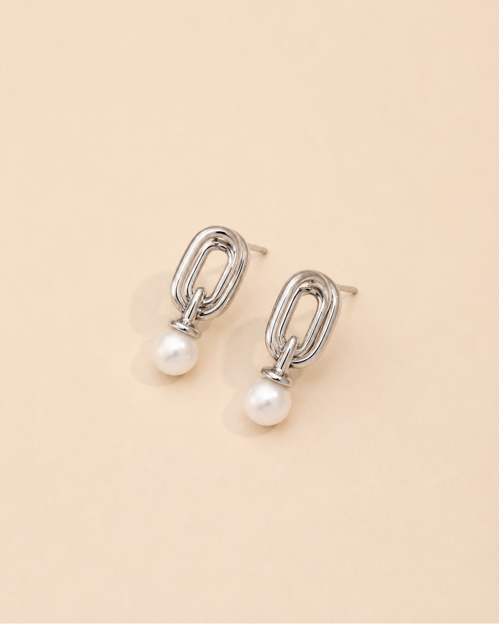 White gold pearl drop earrings crafted from S925 sterling silver with 18K white gold plating and natural freshwater pearls, featuring a contemporary geometric silhouette on a cream background.