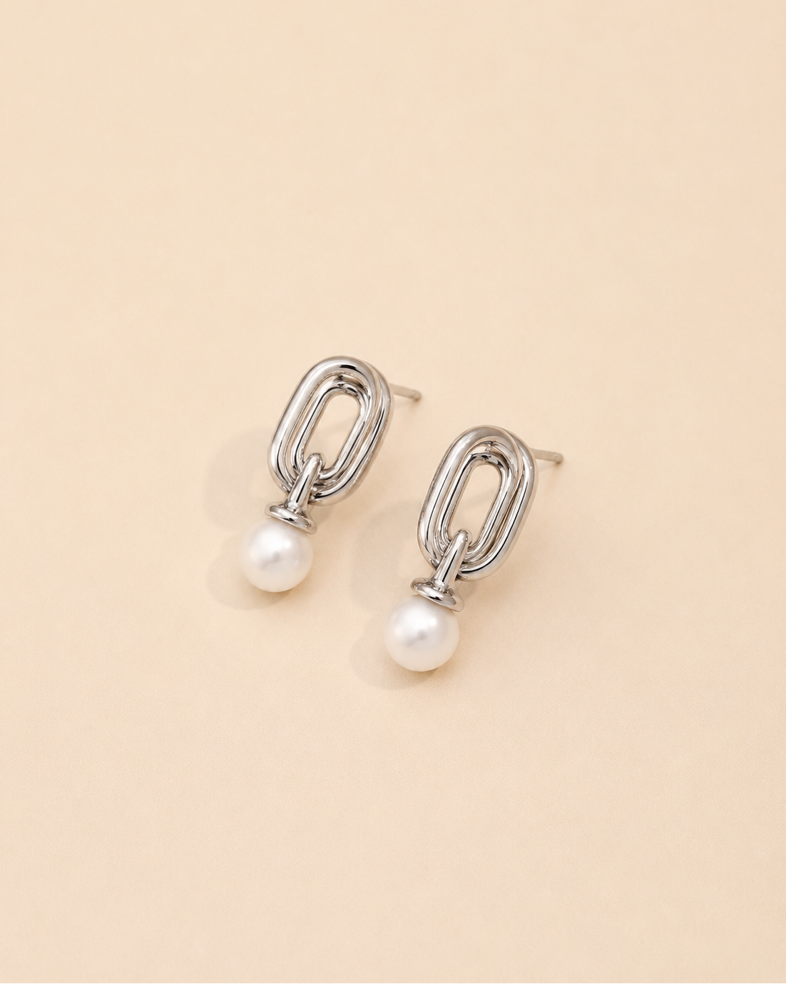 White gold pearl drop earrings crafted from S925 sterling silver with 18K white gold plating and natural freshwater pearls, featuring a contemporary geometric silhouette on a cream background.