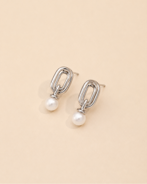 White gold pearl drop earrings crafted from S925 sterling silver with 18K white gold plating and natural freshwater pearls, featuring a contemporary geometric silhouette on a cream background.
