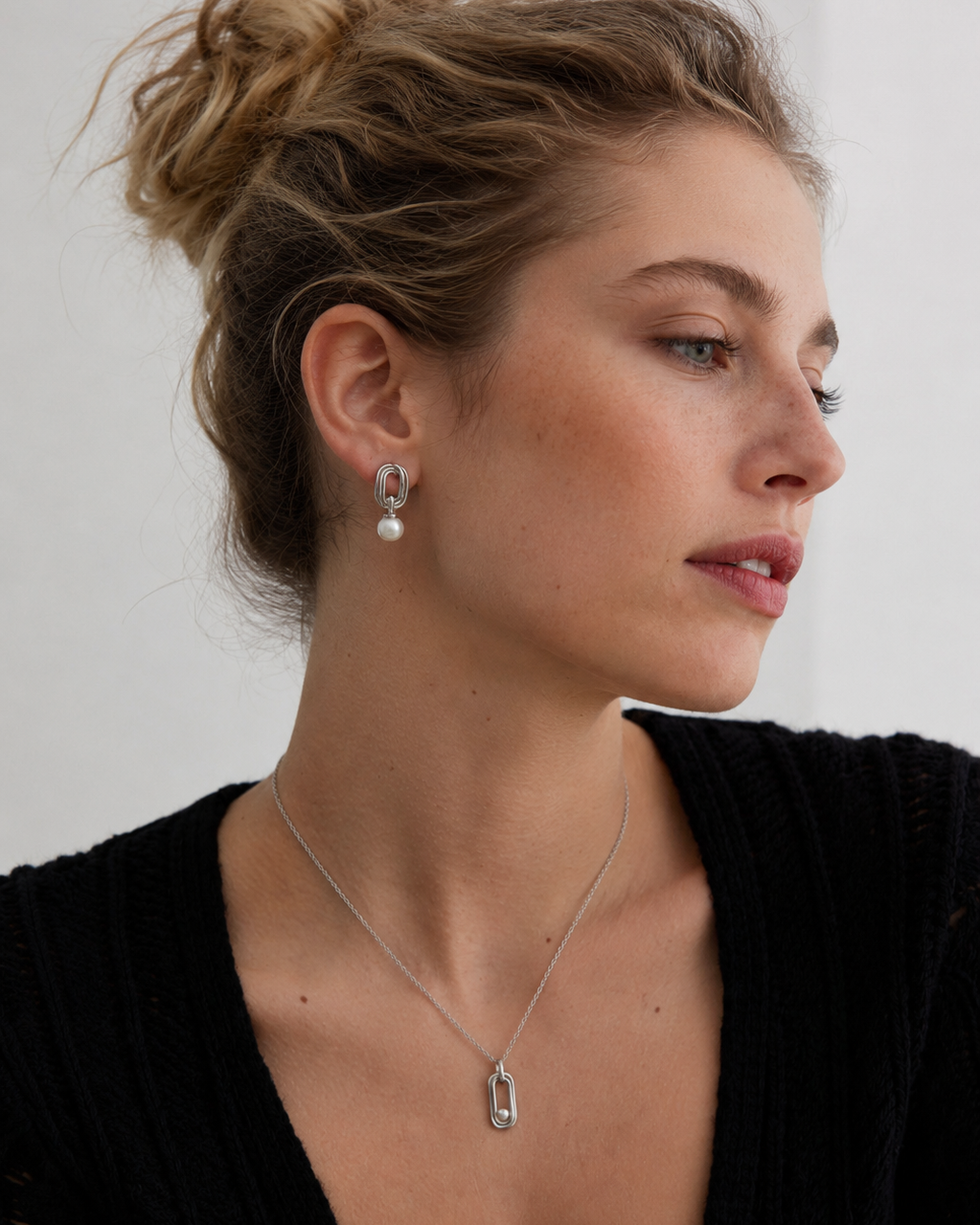 Close-up portrait of a model wearing white gold pearl drop earrings crafted from S925 sterling silver with 18K white gold plating and natural freshwater pearls, styled for an elegant modern look.