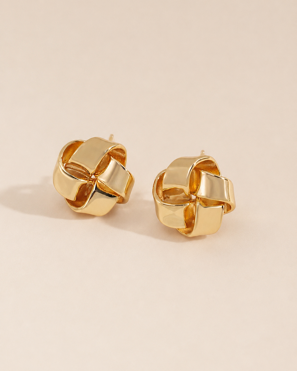 Aurelia Knot gold stud earrings featuring a sculptural woven knot design in polished gold finish.