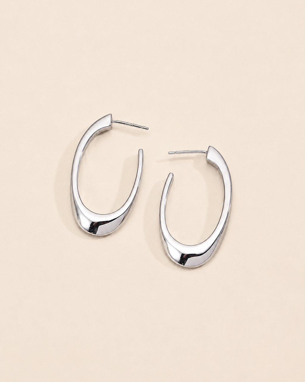 Modern sculptural hoop earrings in sterling silver with a sleek organic silhouette and polished finish.