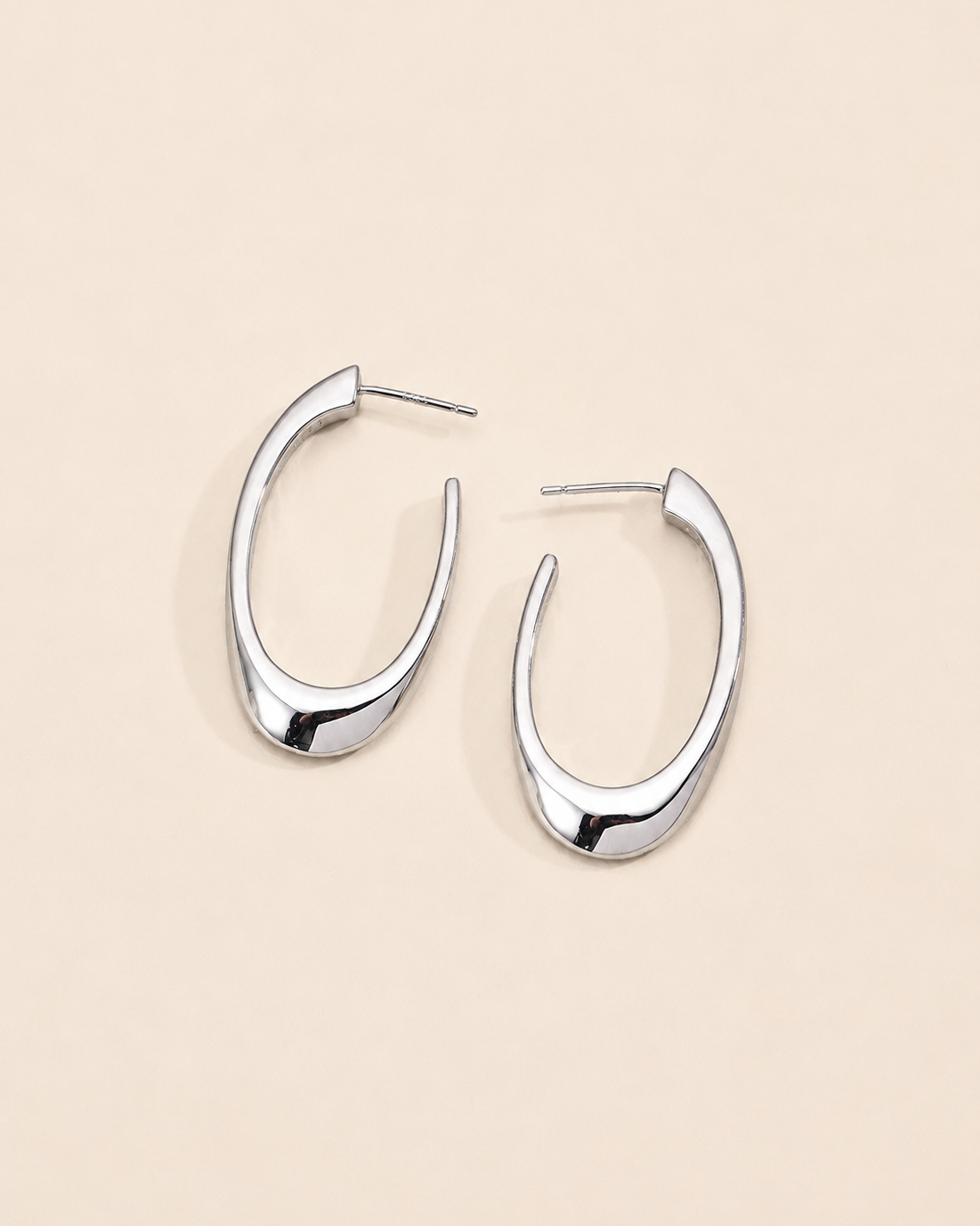 Modern sculptural hoop earrings in sterling silver with a sleek organic silhouette and polished finish.