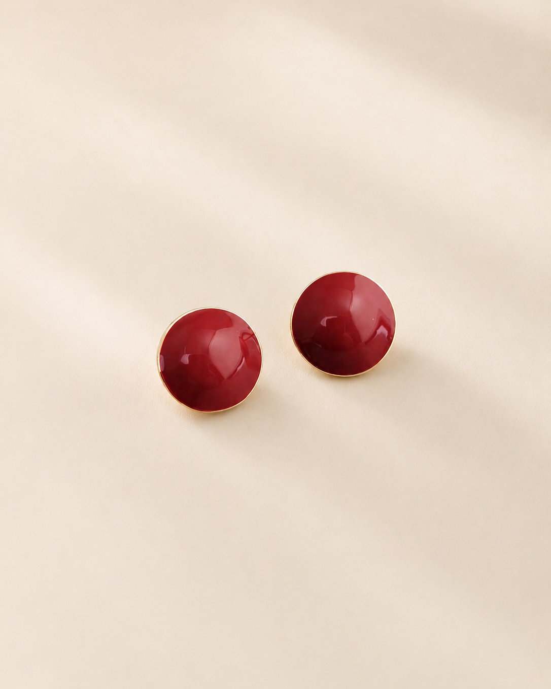 Glossy red enamel stud earrings crafted from S925 sterling silver with thick 18K gold plating, featuring a minimalist round dome design on a soft ivory background.