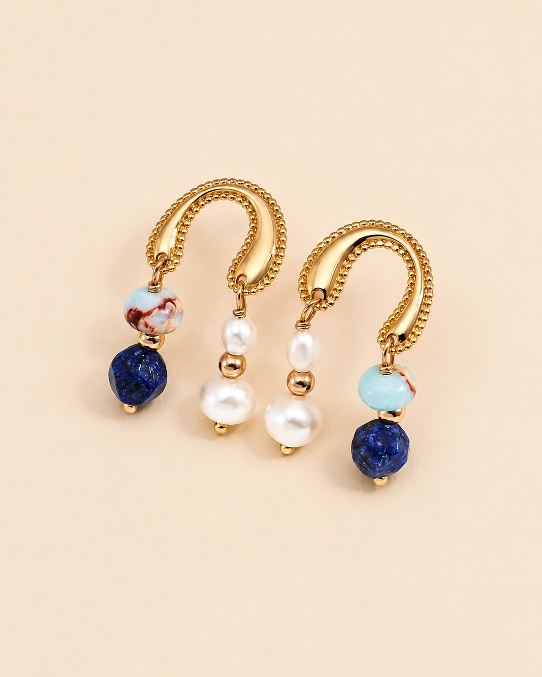 Celeste Arc Earrings in 18K gold vermeil featuring natural freshwater pearls, lapis lazuli and Shoushan stone drops on a soft beige background.