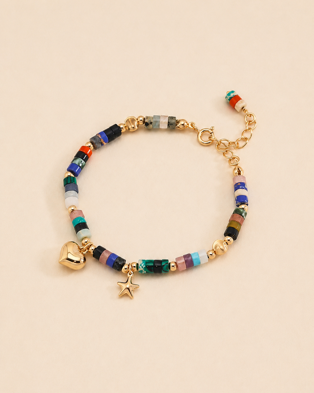 Colorful natural gemstone beaded bracelet with gold heart and star charms in 18K gold plated sterling silver on a soft beige background.
