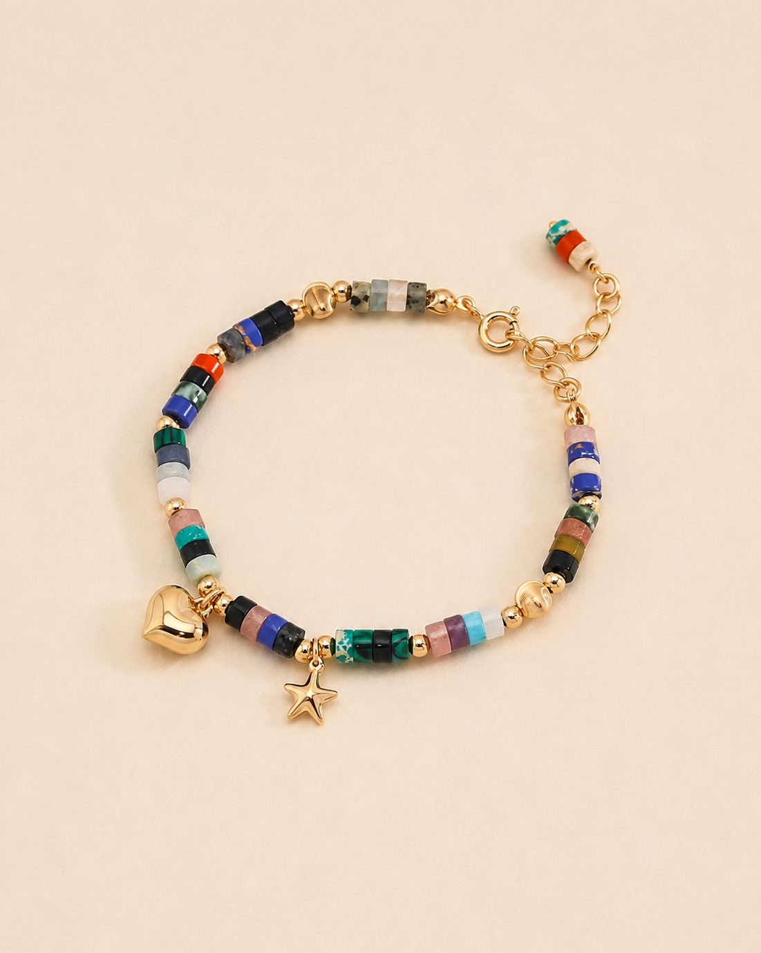 Colorful natural gemstone beaded bracelet with gold heart and star charms in 18K gold plated sterling silver on a soft beige background.