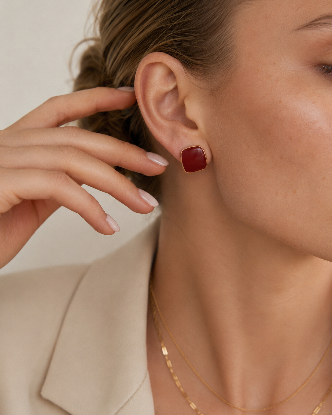 Close-up of a model wearing burgundy enamel stud earrings in S925 sterling silver with thick 18K gold plating.