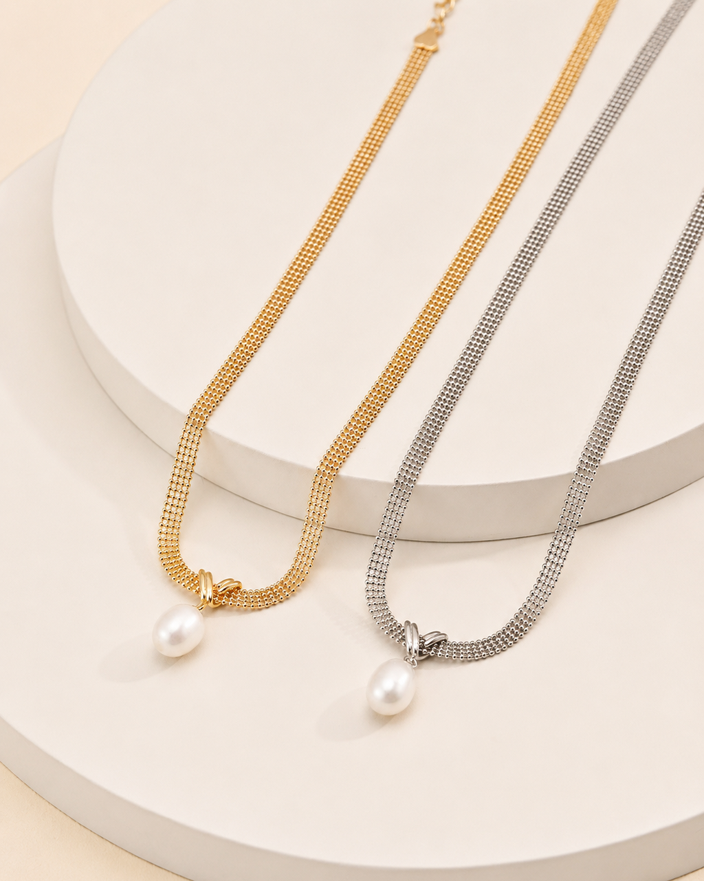 Gold and white gold mesh choker necklaces featuring natural freshwater pearl pendants displayed on a white pedestal.