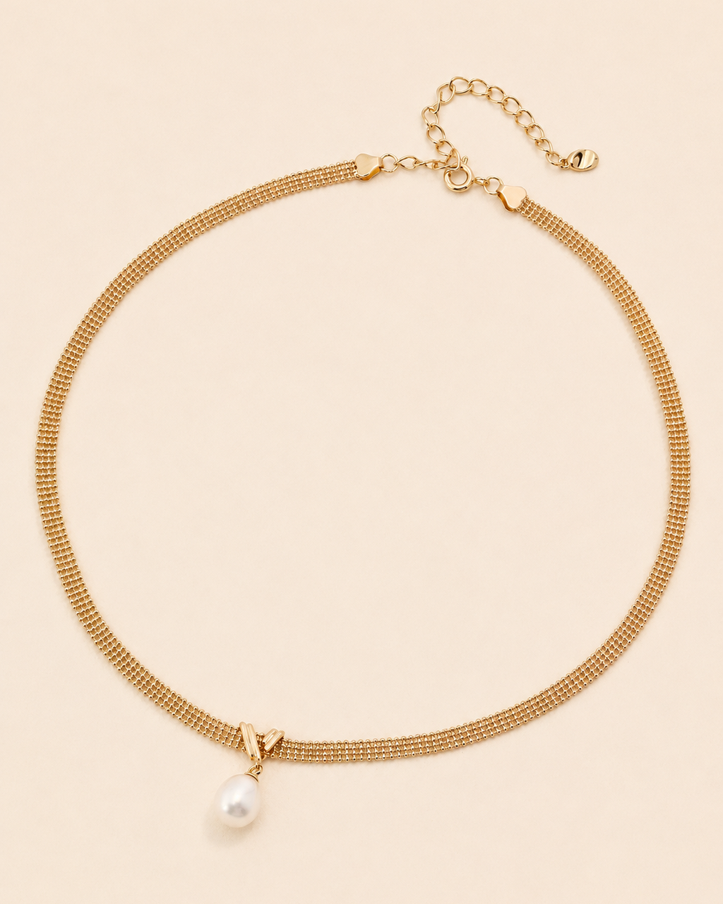 Gold mesh choker necklace with a natural freshwater pearl pendant on a soft cream background.