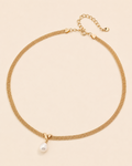 Gold mesh choker necklace with a natural freshwater pearl pendant on a soft cream background.