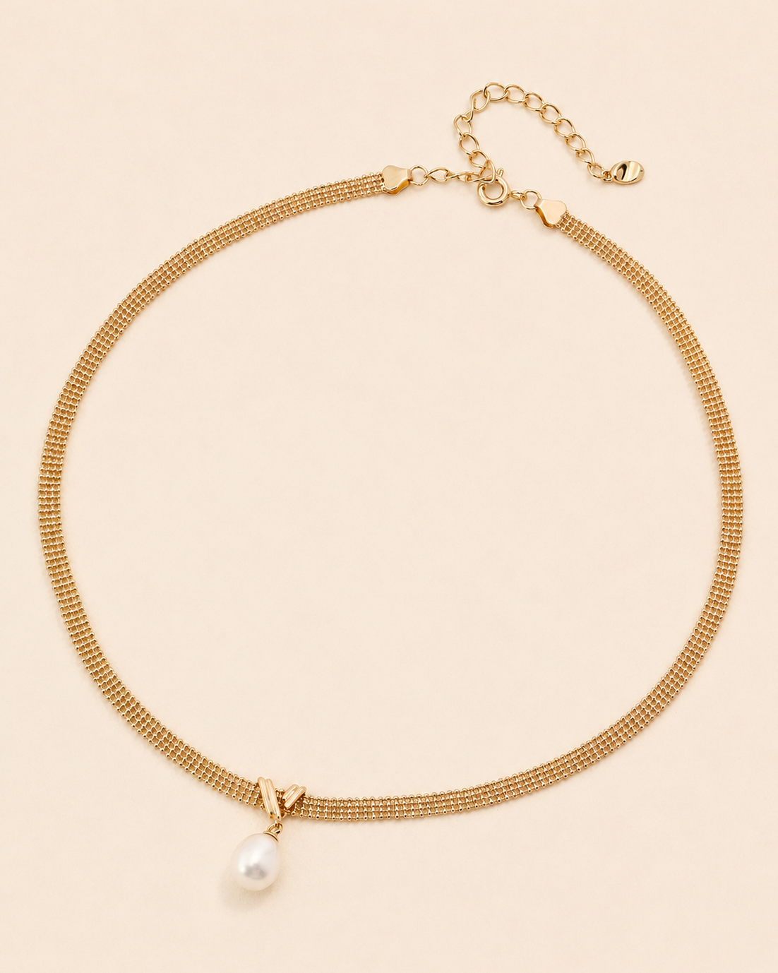Gold mesh choker necklace with a natural freshwater pearl pendant on a soft cream background.