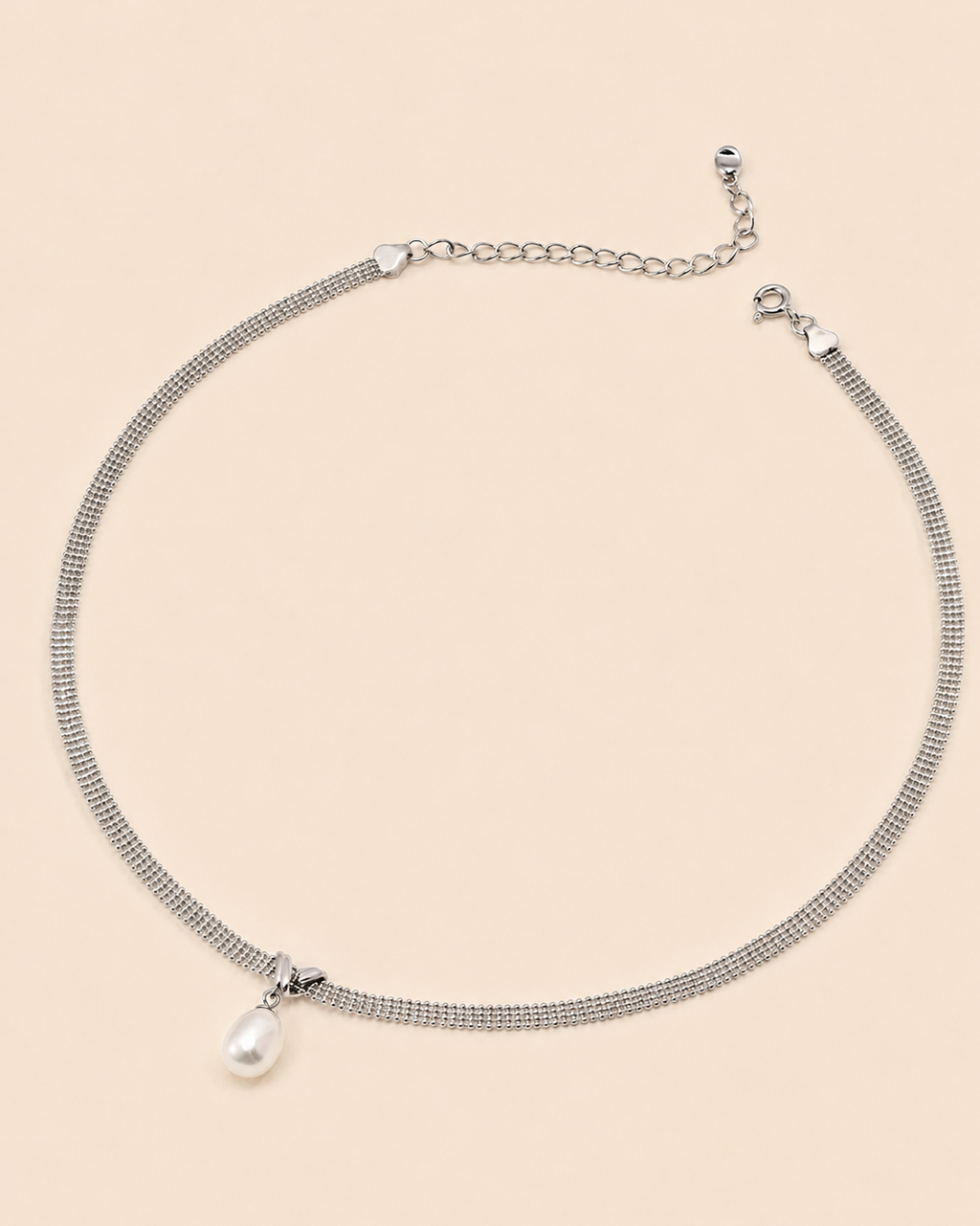 White gold mesh choker necklace with a natural freshwater pearl pendant on a soft cream background.