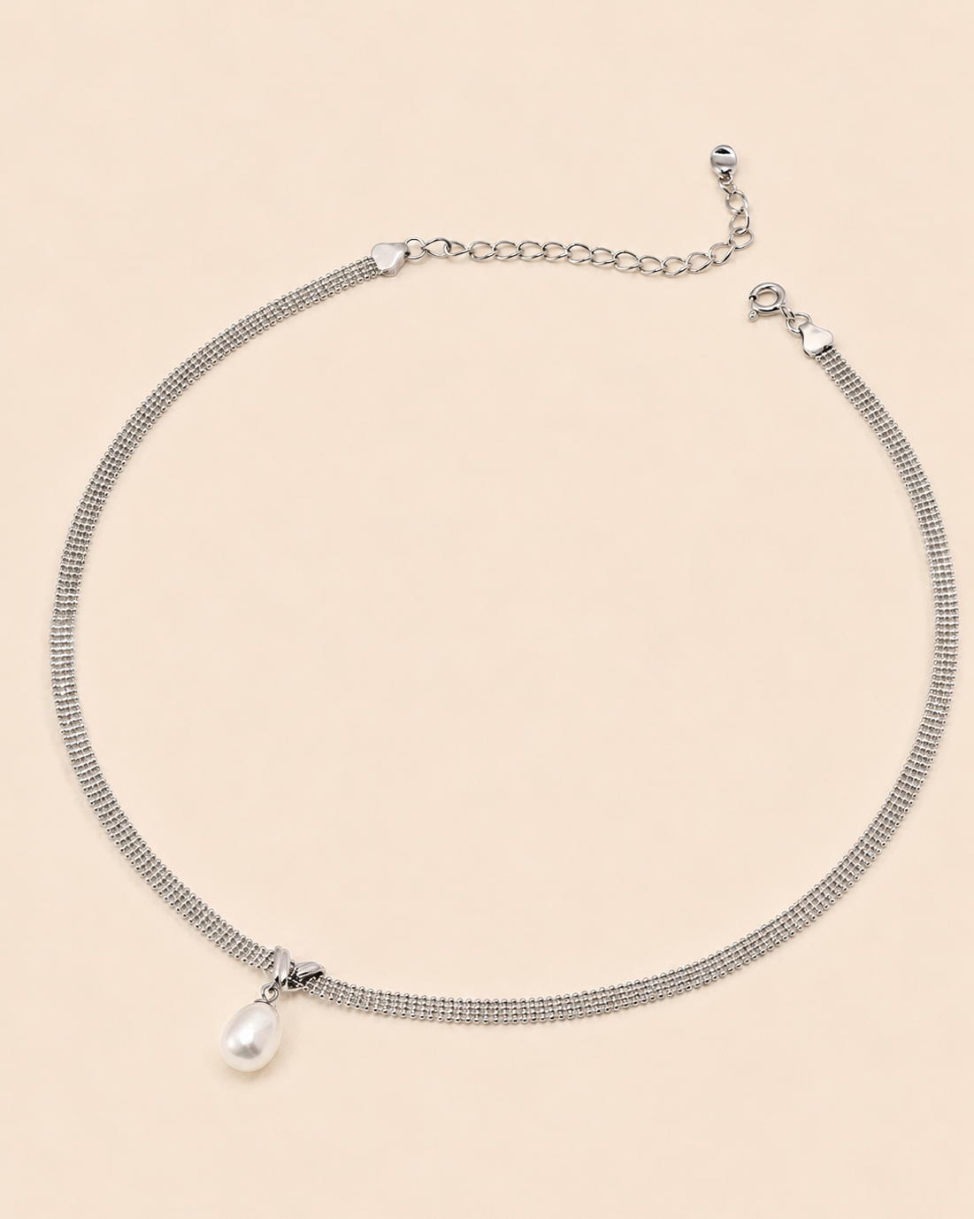 White gold mesh choker necklace with a natural freshwater pearl pendant on a soft cream background.