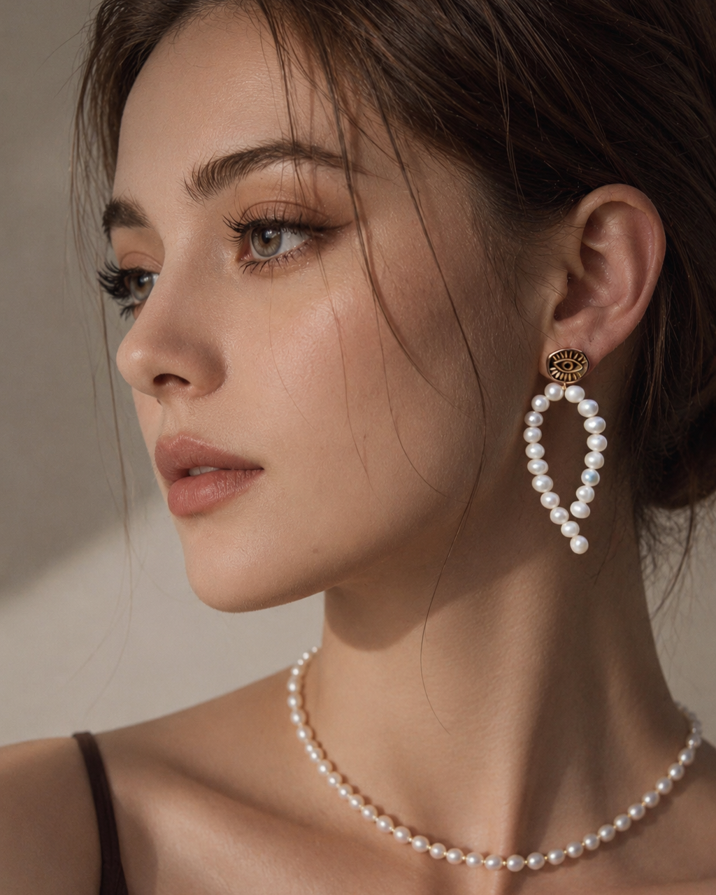 Gold evil eye pearl drop earrings worn by model with freshwater pearl earrings