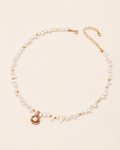 Freshwater pearl necklace featuring a gold camellia flower pendant with a pearl center, displayed on a soft ivory background with an adjustable extension chain.