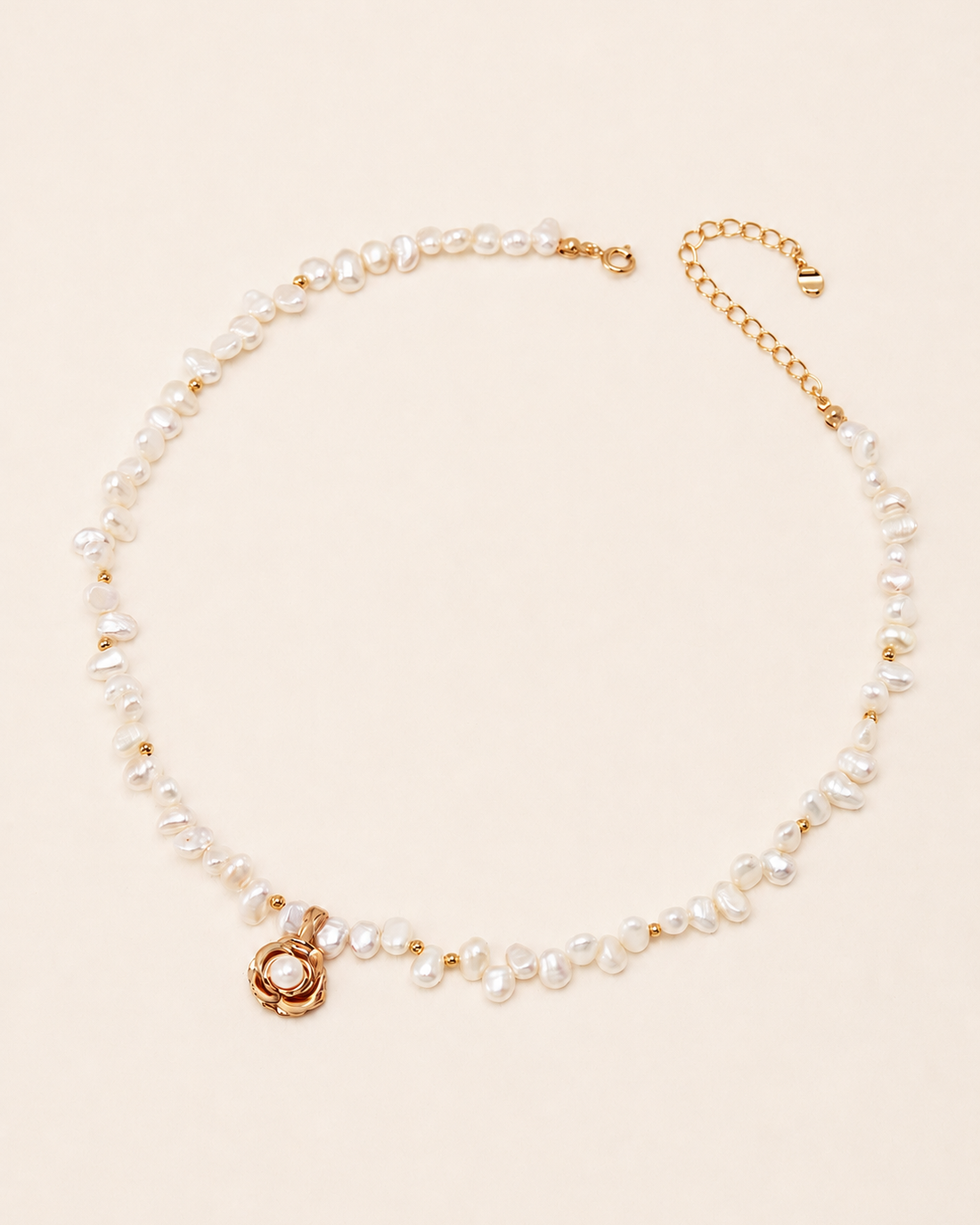 Freshwater pearl necklace featuring a gold camellia flower pendant with a pearl center, displayed on a soft ivory background with an adjustable extension chain.
