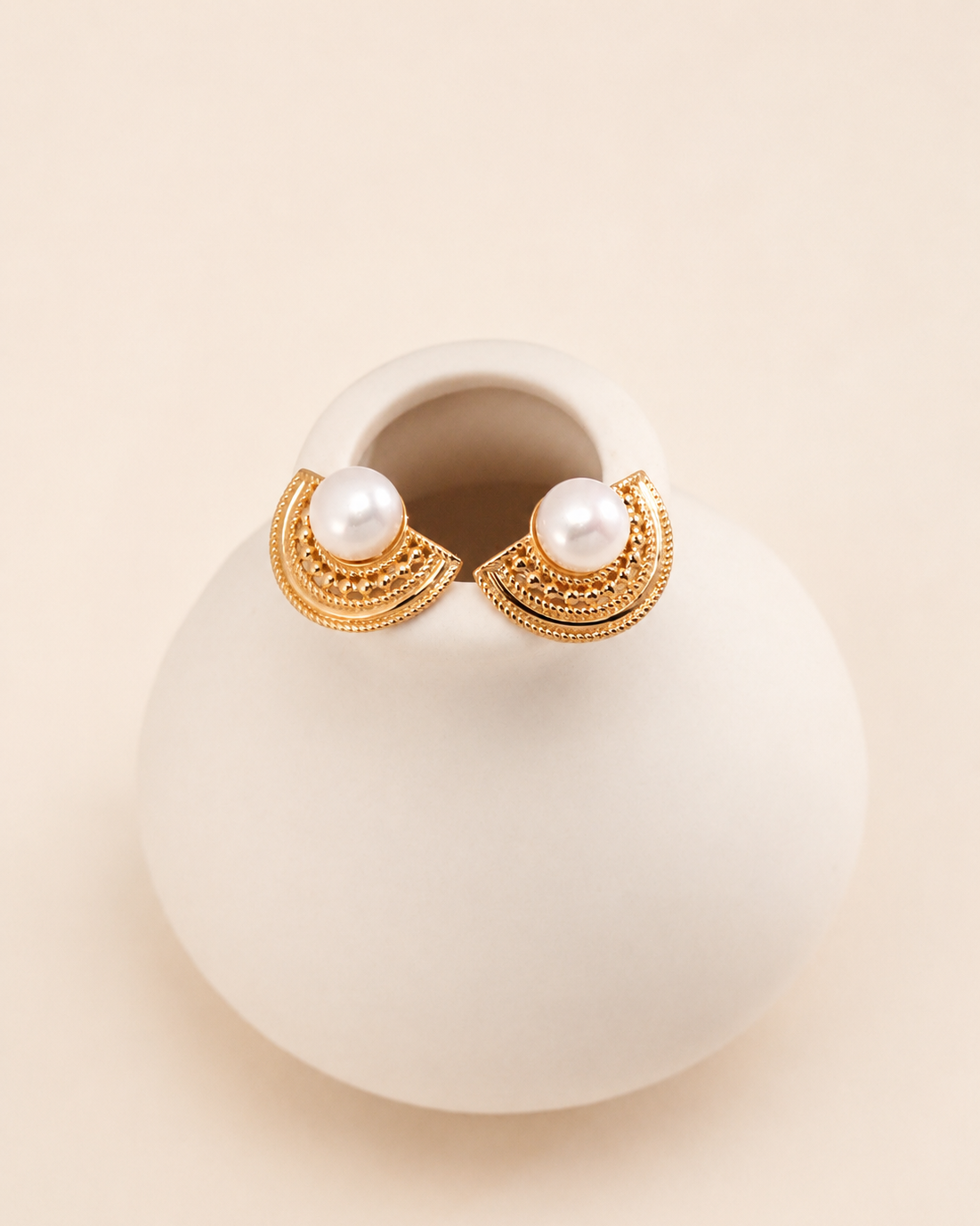 Elegant gold fan-shaped pearl stud earrings featuring intricate filigree details and a luminous pearl center