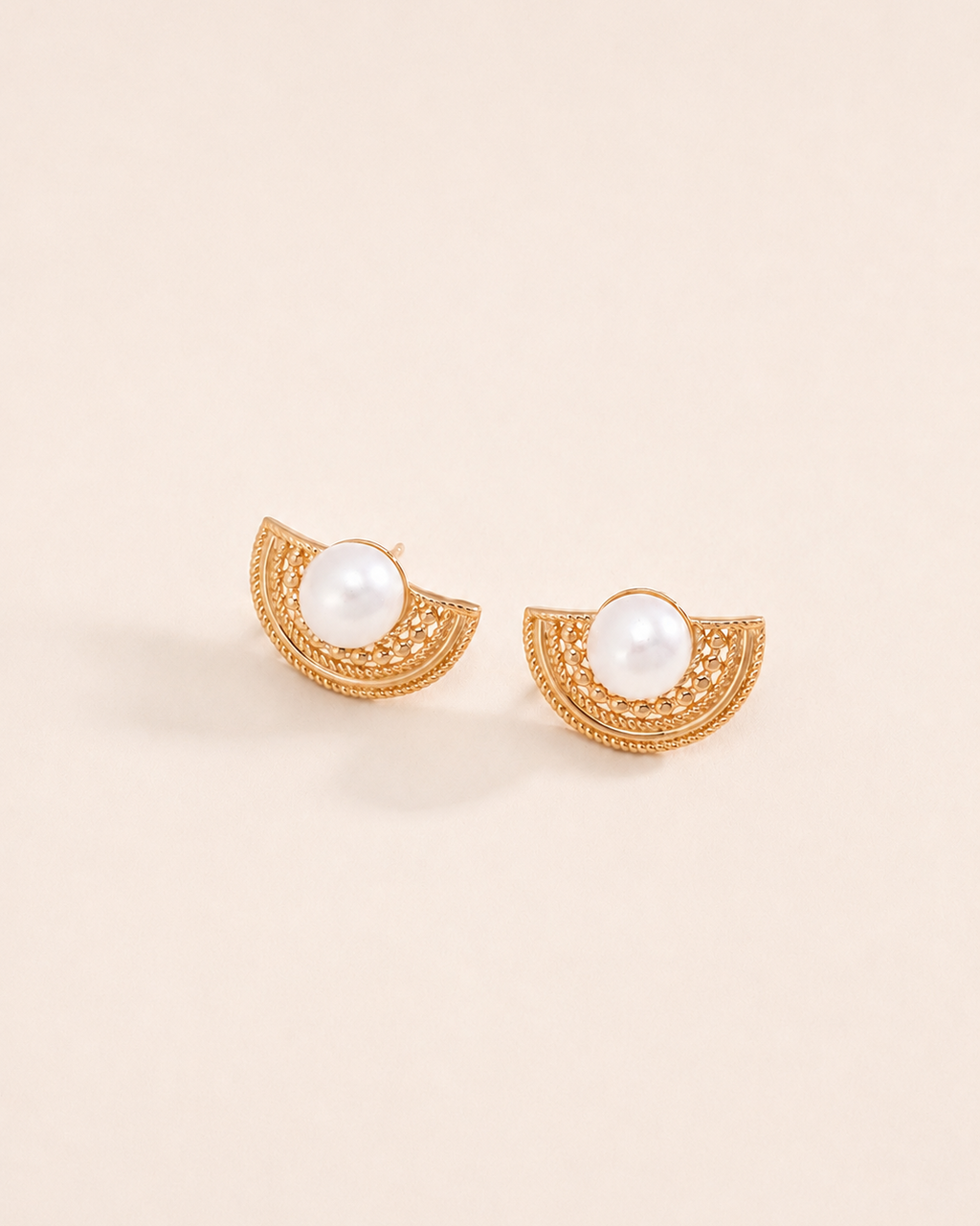 Gold vintage fan stud earrings with pearl centerpiece on a soft ivory background