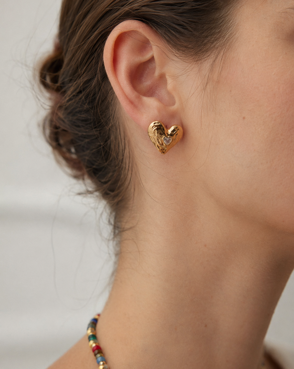 Model wearing Lumi Heart Stud Earrings in thick 18K gold plated S925 sterling silver with sparkling heart-shaped cubic zirconia.