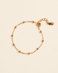 Delicate gold vermeil satellite chain bracelet with polished bead accents on a soft cream background.