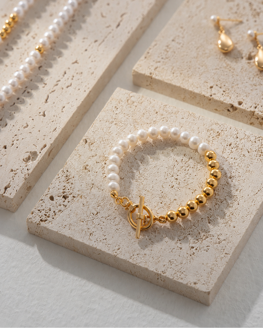Luna Pearl T-Bar Bracelet featuring natural freshwater pearls and thick 18K gold plated sterling silver displayed on a textured stone surface.