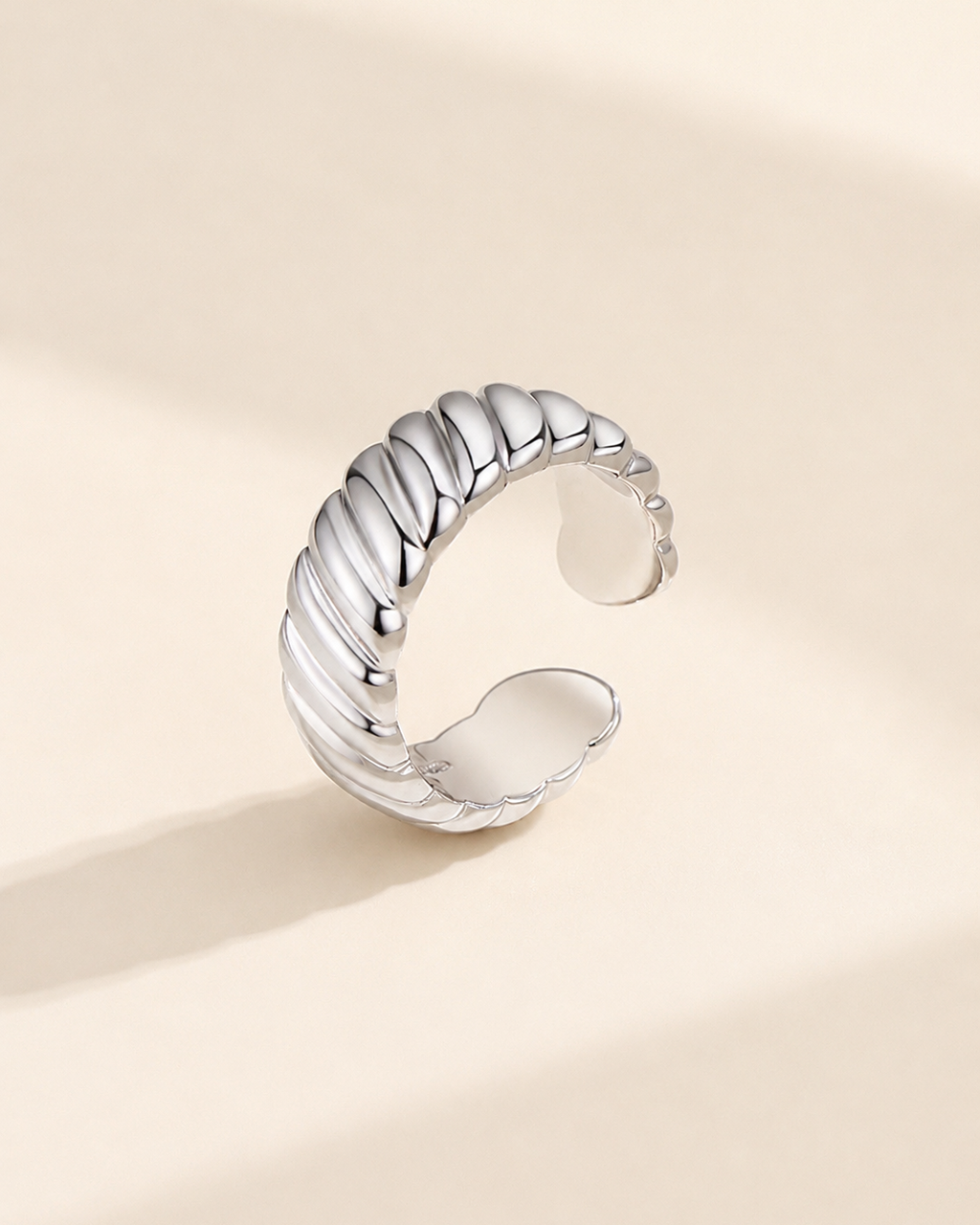 Adjustable rope texture ring in S925 sterling silver with thick 18K white gold plating on a soft ivory background.