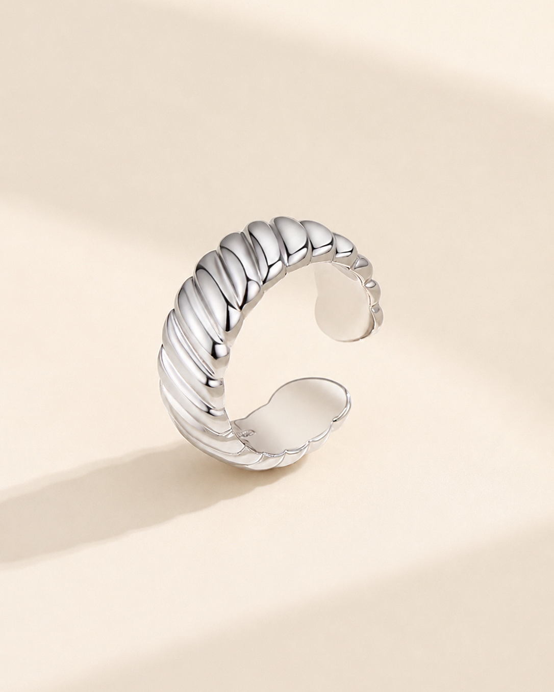 Adjustable rope texture ring in S925 sterling silver with thick 18K white gold plating on a soft ivory background.