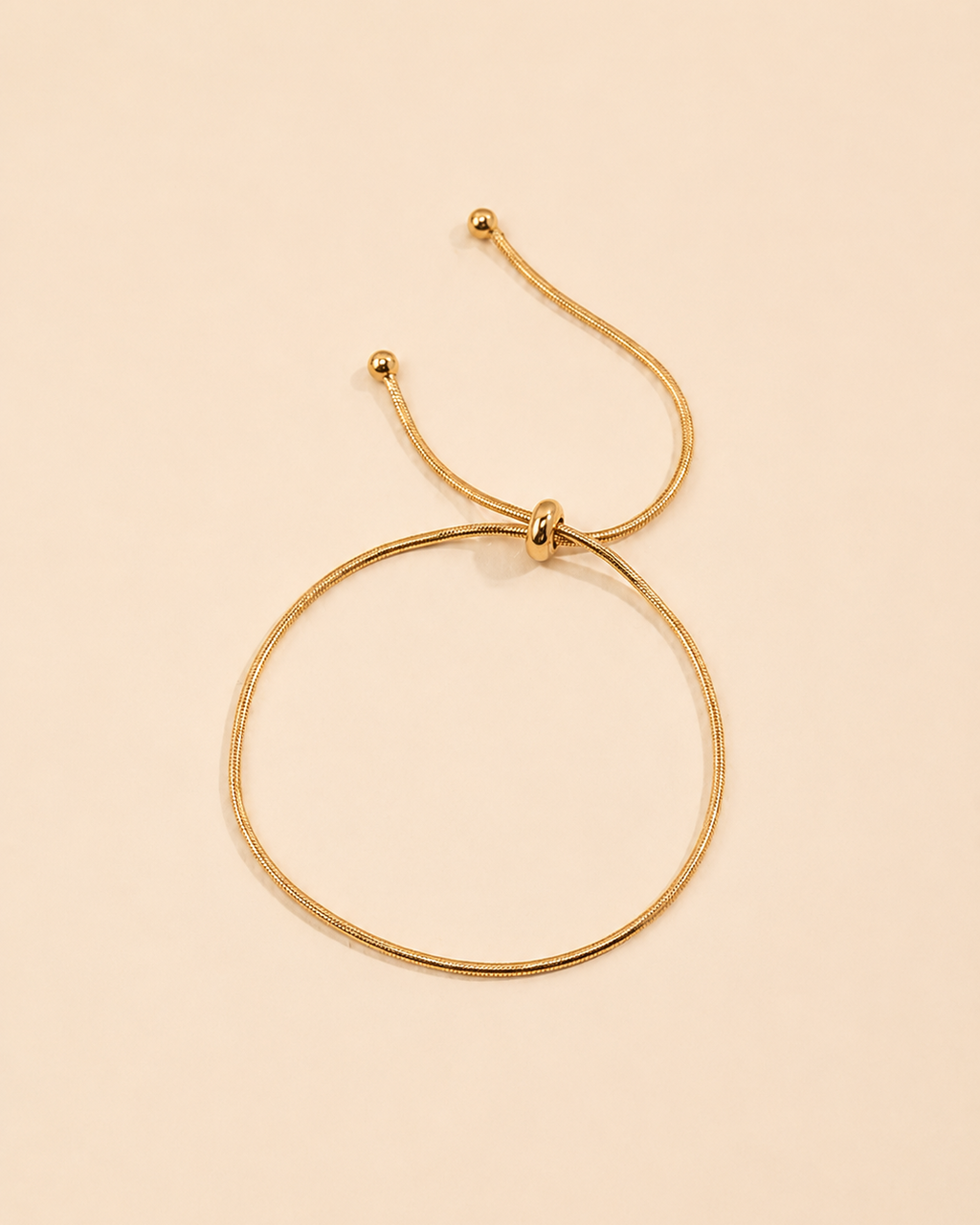 Adjustable gold snake chain bracelet featuring a sleek slider closure and minimalist design.