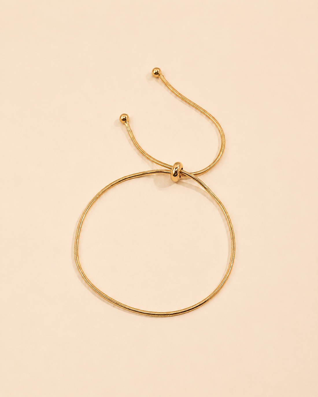 Adjustable gold snake chain bracelet featuring a sleek slider closure and minimalist design.