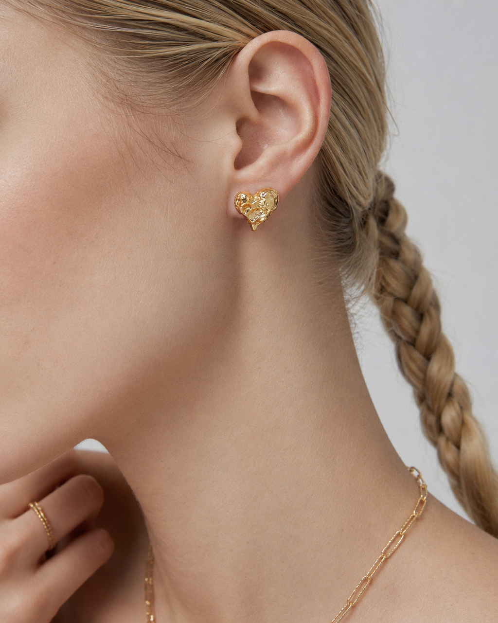 Model wearing Melted Heart stud earrings in thick 18K gold plating, featuring a sculptural organic heart design for everyday elegance.