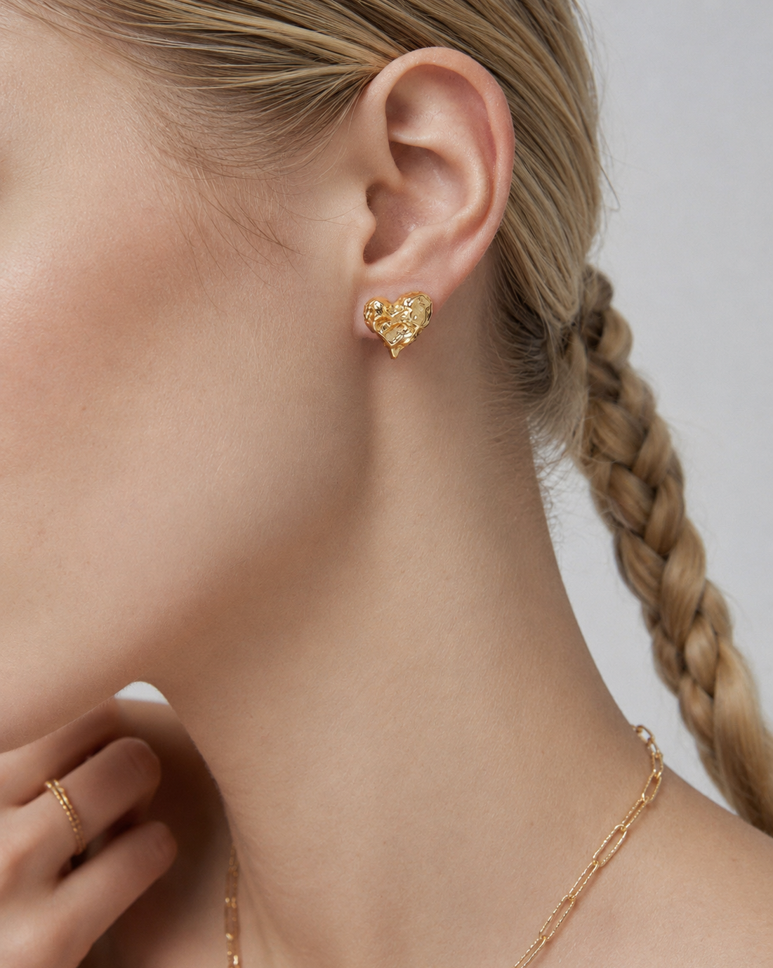 Model wearing Melted Heart stud earrings in thick 18K gold plating, featuring a sculptural organic heart design for everyday elegance.