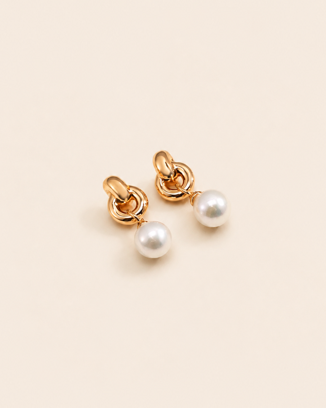 Pair of NORA Pearl Earrings with gold knot detailing and luminous freshwater pearl drops.