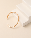 Nova Open Cuff in thick 18K gold plated S925 sterling silver displayed on a minimalist ivory pedestal.