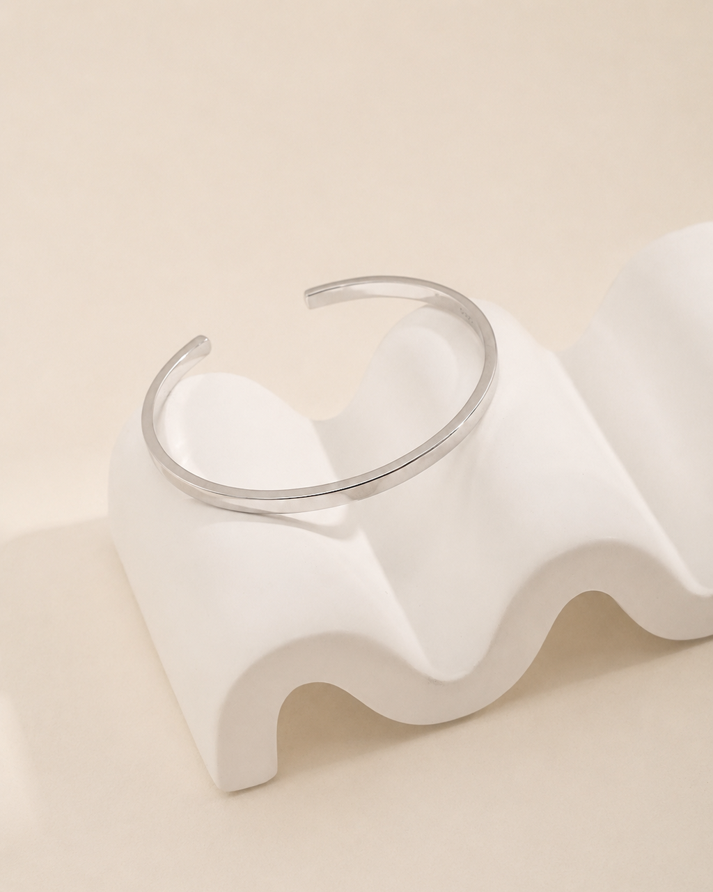Nova Open Cuff in 18K white gold plated S925 sterling silver displayed on a sculptural ivory pedestal.