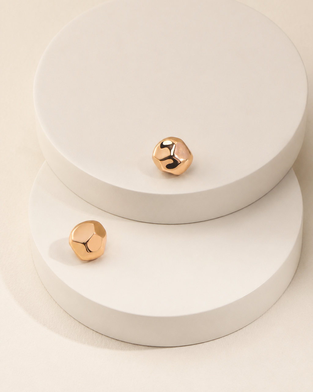 Organic gold stud earrings in thick 18K gold plating featuring a modern sculptural pebble-inspired design on a soft beige background.