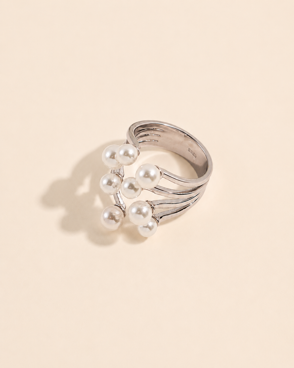 White gold adjustable ring featuring a cluster of shell pearls on a beige background