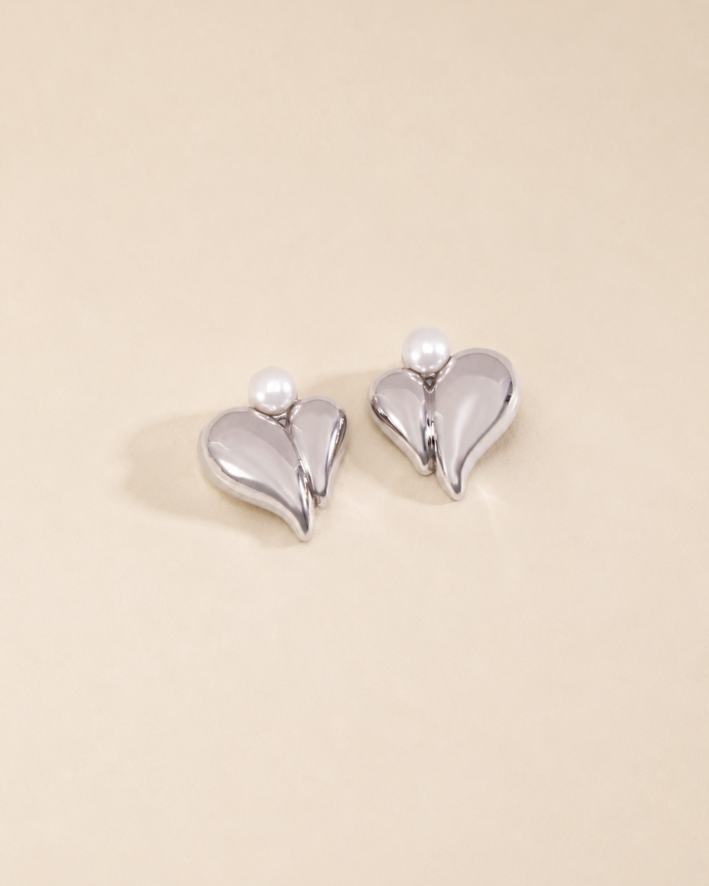 Pearl heart stud earrings in white gold finish with natural freshwater pearls on a soft ivory background.
