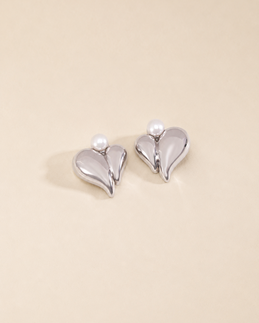 Pearl heart stud earrings in white gold finish with natural freshwater pearls on a soft ivory background.